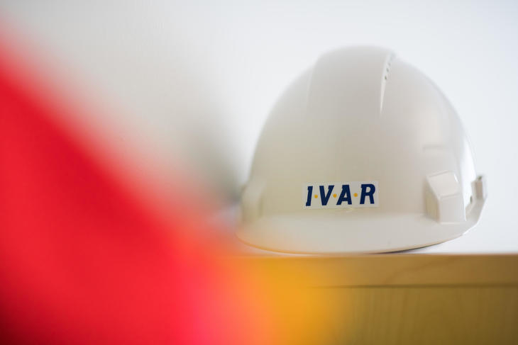Hvit arbeidshjelm med IVAR-logo. 